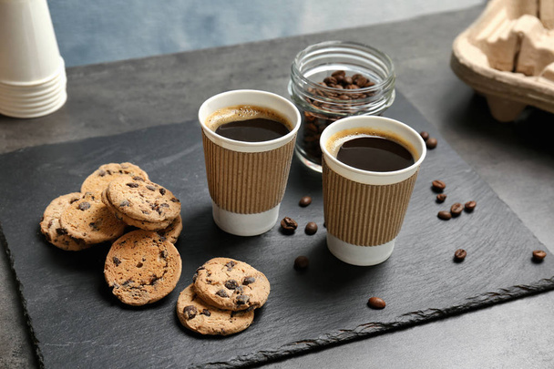 Composition with aromatic hot coffee in paper cups and cookies on table - Foto, imagen