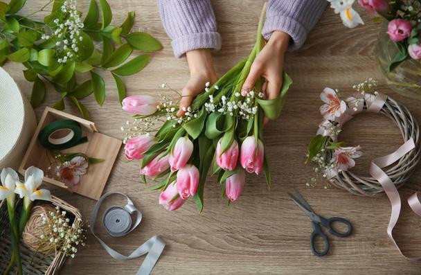Female decorator creating beautiful bouquet at table, top view - Photo, Image