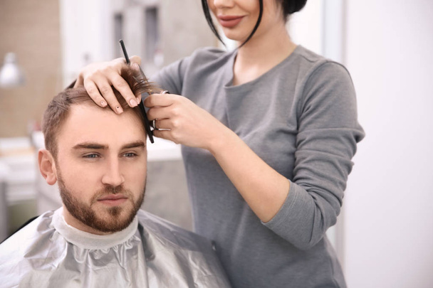 Professional female hairdresser working with client in salon - Photo, image