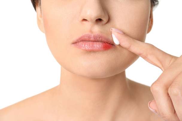 Woman applying cream onto lips on white background, closeup - Foto, imagen
