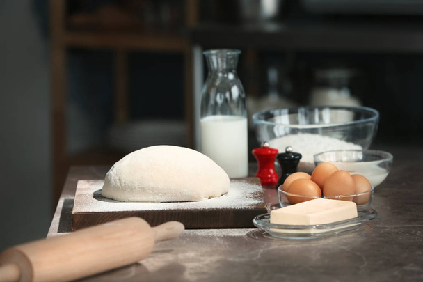 Dough covered with flour and ingredients on table in kitchen - Photo, Image