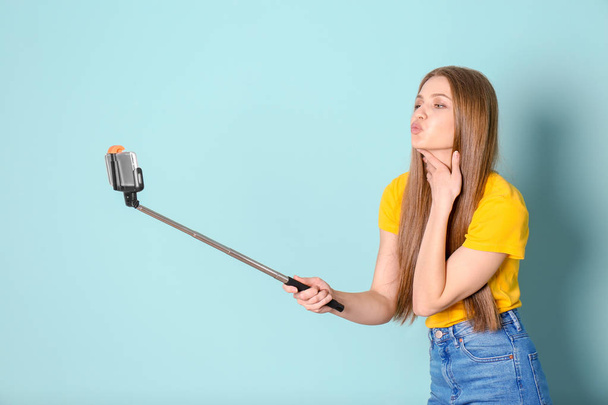 Young beautiful woman taking selfie against color background - Fotó, kép