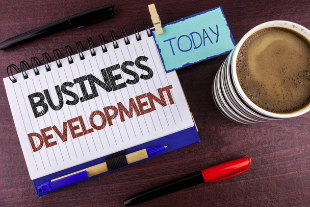Tekstiä kirjoittava teksti Business Development. Liiketoiminta käsite kehittää ja toteuttaa organisaation kasvumahdollisuuksia kirjoitettu Notepad puinen tausta tänään Clip Pen Marker Coffee Cup
 - Valokuva, kuva