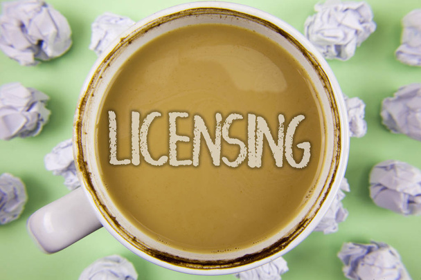 Tekst pisma Licencjonowanie. Koncepcję co oznacza prawnie udziela licencji pozwalają na korzystanie ze coś Zezwalaj aktywność napisane na herbatę w White Cup w zmięty papier kulki na zwykły tło zielony. - Zdjęcie, obraz