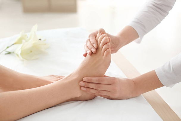 Jeune femme bénéficiant d'un massage des pieds dans le salon de spa, se concentrer sur les jambes
 - Photo, image