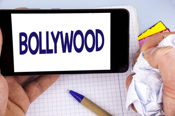 Manuscrito de texto de Bollywood. Conceito que significa cinema indiano uma fonte de entretenimento escrito no celular Tela segurando por homem em fundo simples Notebook Pen
 - Foto, Imagem