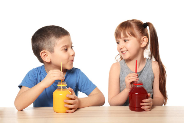 白い背景の上のテーブルで柑橘類のジュースを飲むかわいい子供たち - 写真・画像