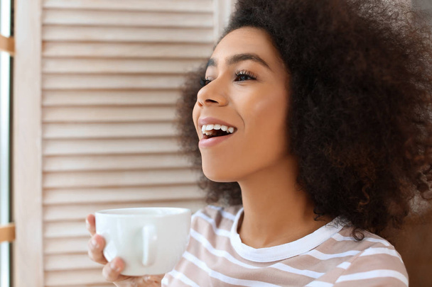 Mulher afro-americana bonita bebendo chá dentro de casa
 - Foto, Imagem