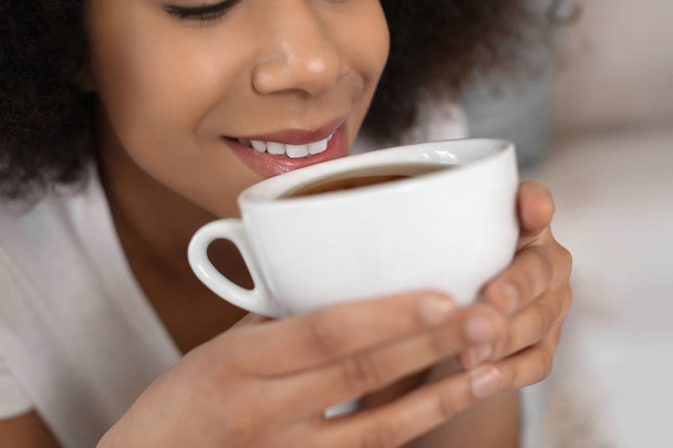 schöne afrikanisch-amerikanische Frau trinkt Tee drinnen, Nahaufnahme - Foto, Bild