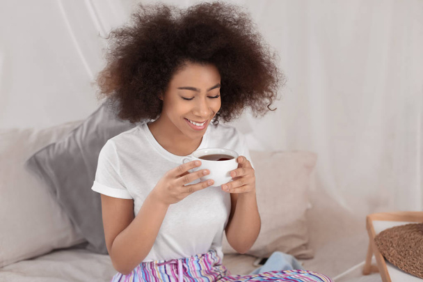 Belle femme afro-américaine buvant du thé à la maison
 - Photo, image