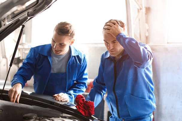 Male mechanics fixing car in service center - Foto, imagen