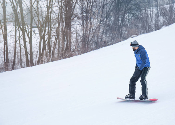 Hombre snowboarder en pendiente en estación de invierno
 - Foto, Imagen