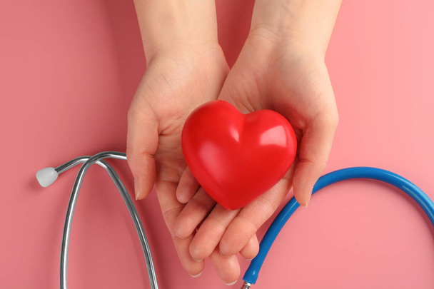 Female hands with small heart and stethoscope on color background - Photo, Image