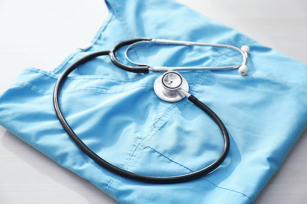 Stethoscoop met blauwe arts is uniform op tafel - Foto, afbeelding