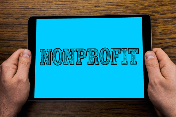 Nonprofit gösterilen metin işareti. Kavramsal fotoğraf gelirleri Tablet ekran tutarak el ahşap arka plan üzerinde yazılı executor için üretemeyen faaliyetleri. - Fotoğraf, Görsel