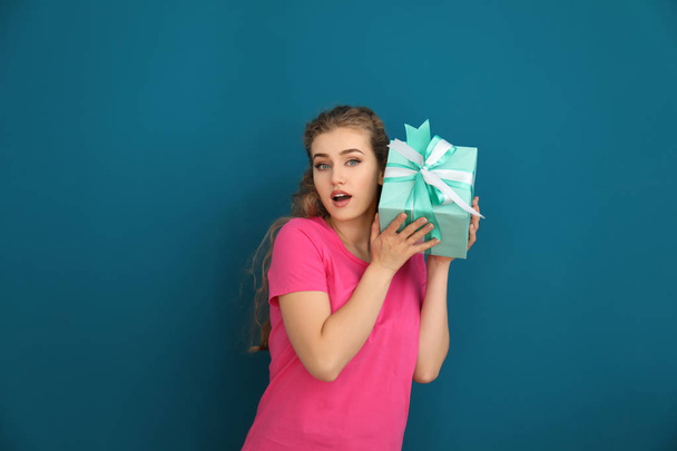 Beautiful young woman with gift box on color background - Photo, Image
