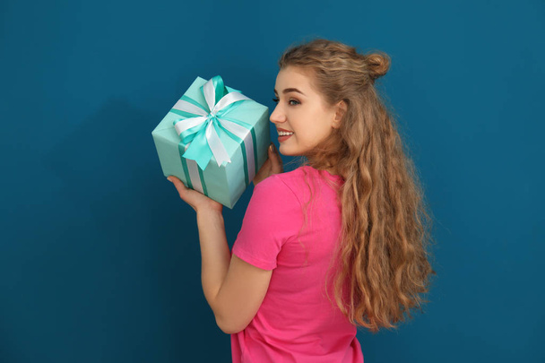 Beautiful young woman with gift box on color background - Foto, Imagen