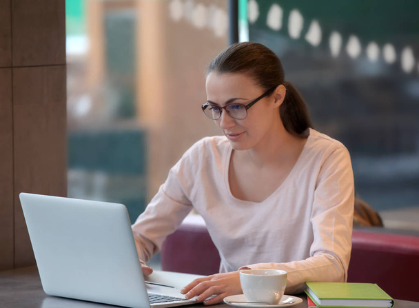 Jeune pigiste avec ordinateur portable travaillant dans un café
 - Photo, image