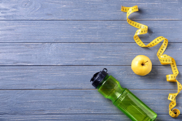 flache Liegekomposition mit Flasche Wasser, Apfel und Maßband auf Holzgrund. Fitnesstraining - Foto, Bild