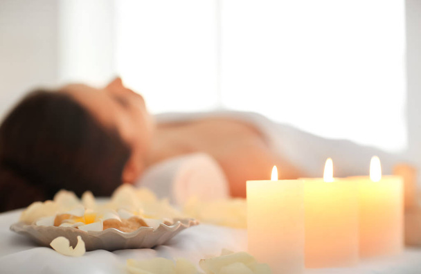 Vonné svíčky, květiny a uvolněná žena ve spa salonu - Fotografie, Obrázek