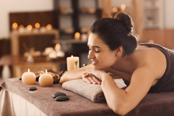 jonge vrouw ontspannen op massagetafel op spa salon - Foto, afbeelding