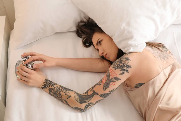 Young woman with alarm clock in bed. Early morning - Foto, Bild