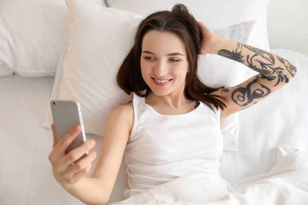 Jovem bela mulher tomando selfie na cama de manhã
 - Foto, Imagem