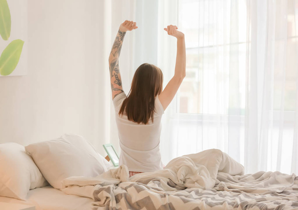 Молодая красивая женщина растягивается на кровати утром
 - Фото, изображение