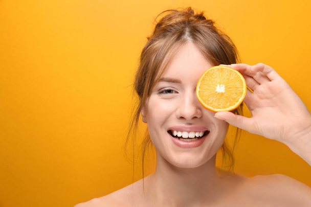Beautiful young woman with citrus fruit on color background - Foto, Bild