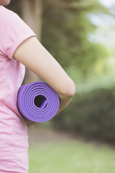 Young woman holding a yoga mat in exercise class for a sport and - Fotografie, Obrázek