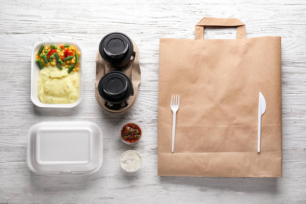 Lezzetli yemek, karton bardak ve çanta ahşap masa üzerinde plastik kaplar. Teslimat hizmeti - Fotoğraf, Görsel