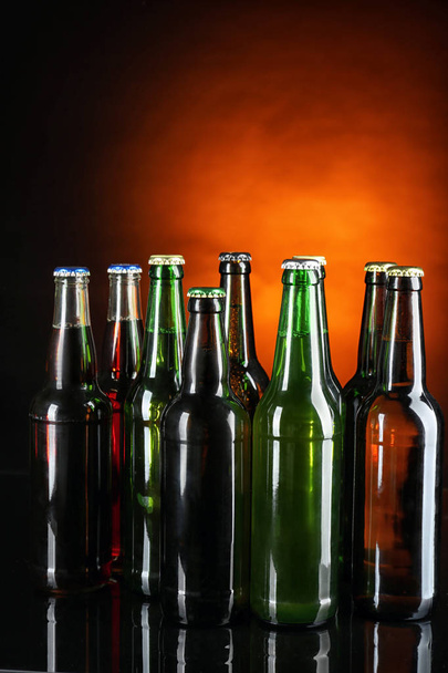 Φρέσκια μπύρα σε γυάλινες φιάλες σε σκούρο φόντο - Φωτογραφία, εικόνα