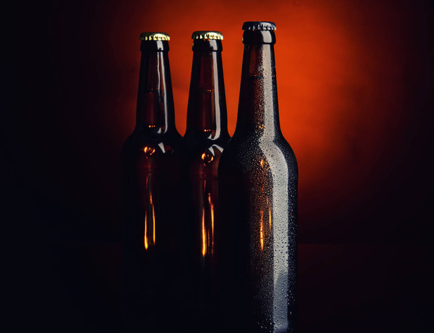 Bière fraîche en bouteilles de verre sur fond sombre
 - Photo, image