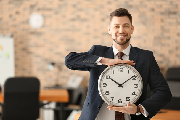 Homme d'affaires mature avec horloge au bureau. Concept de gestion du temps
 - Photo, image