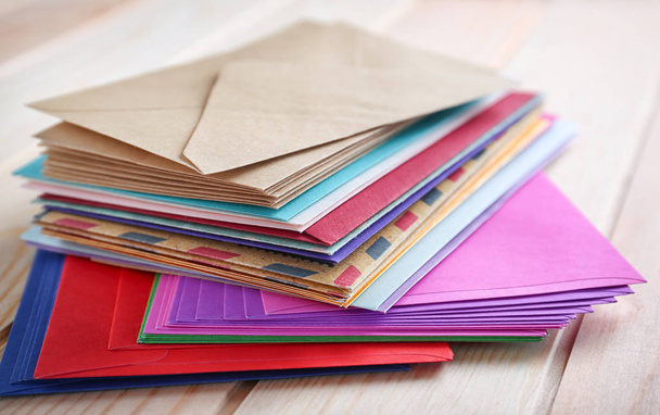 Stack of colorful envelopes on wooden table, closeup. Mail service - Fotó, kép