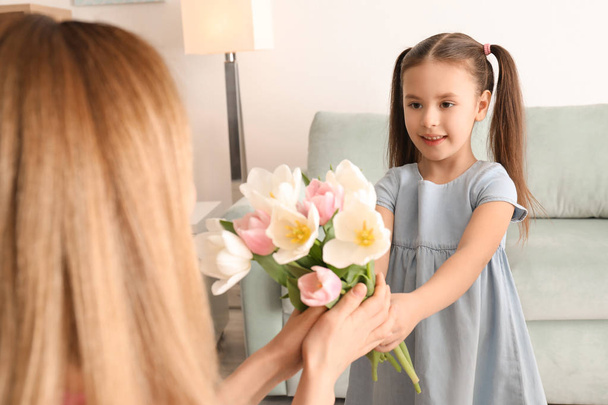 Mother receiving flowers from her cute little daughter at home - Foto, Imagem