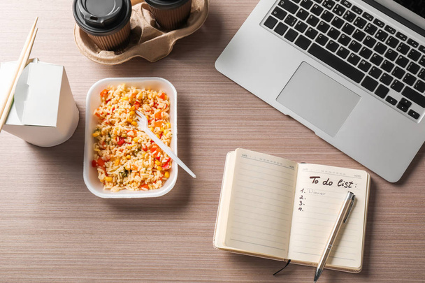Containers met heerlijke maaltijden, notitieboekje en laptop op tafel. Concept van voedsel levering online - Foto, afbeelding