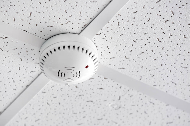 Modern smoke detector on ceiling indoors - Photo, Image