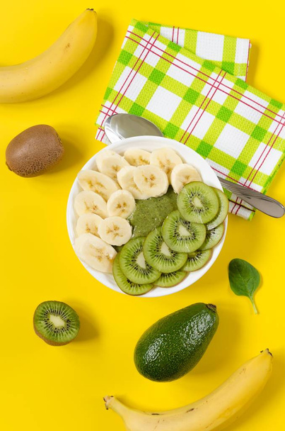 Green smoothie in a white bowl on yellow background - Fotó, kép