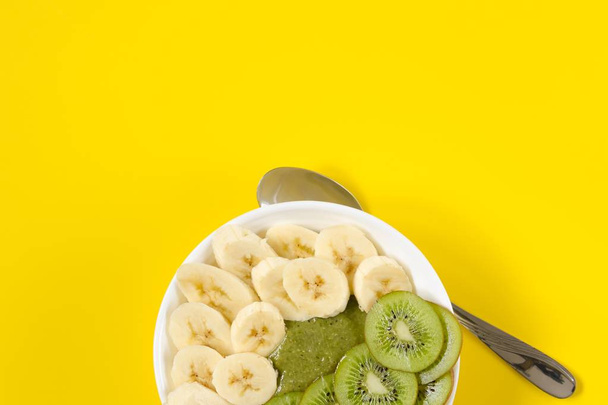 Green smoothie in a white bowl on yellow background - Zdjęcie, obraz