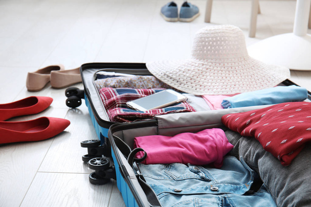 Valise ouverte avec vêtements et chaussures féminines sur le sol
 - Photo, image