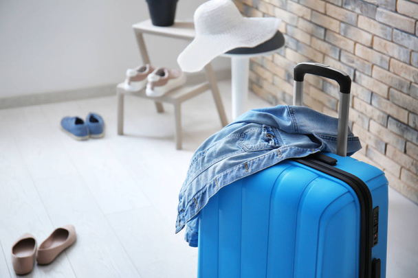 Συσκευασμένα βαλίτσα και τζιν σακάκι στο δωμάτιο - Φωτογραφία, εικόνα