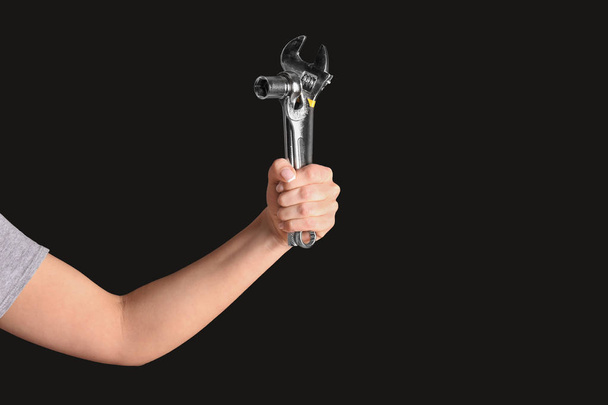 Hand of female car mechanic with tools on black background - Foto, imagen