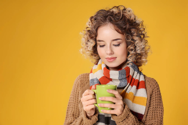 Porträt einer schönen jungen Frau mit einer Tasse heißen Kaffees auf farbigem Hintergrund - Foto, Bild