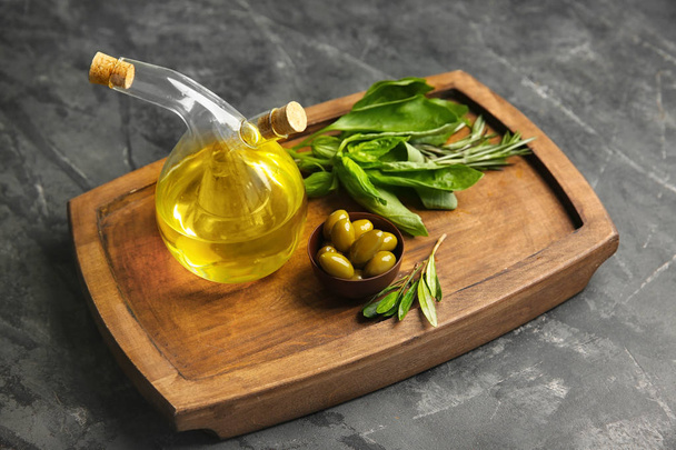 Bottle with oil and olives on wooden board - Фото, зображення