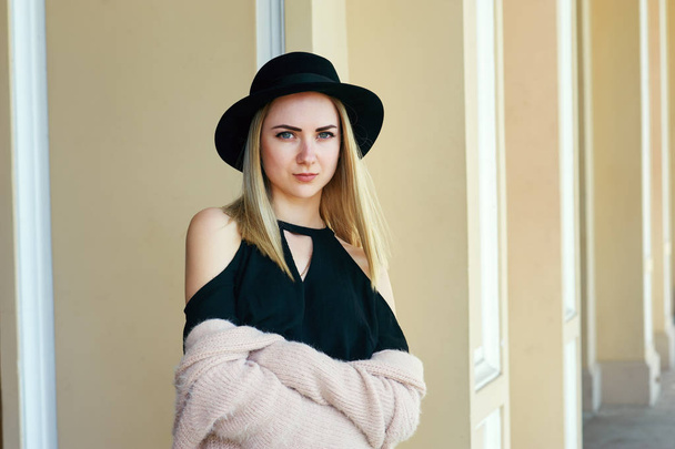 close-up portrait of a young beautiful fashionable woman posing on the street. Model in a stylish hat on the streets . Women's fashion - Φωτογραφία, εικόνα