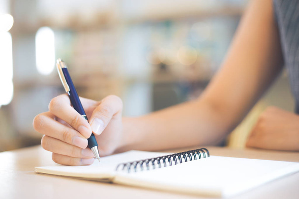 Mão de mulher de negócios está escrevendo em um bloco de notas com uma caneta em offic
 - Foto, Imagem