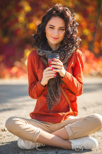 秋の背景にて紅茶やコーヒーのカップの若くてきれいな女性。魅力的な若い女の子屋外の肖像画 - 写真・画像