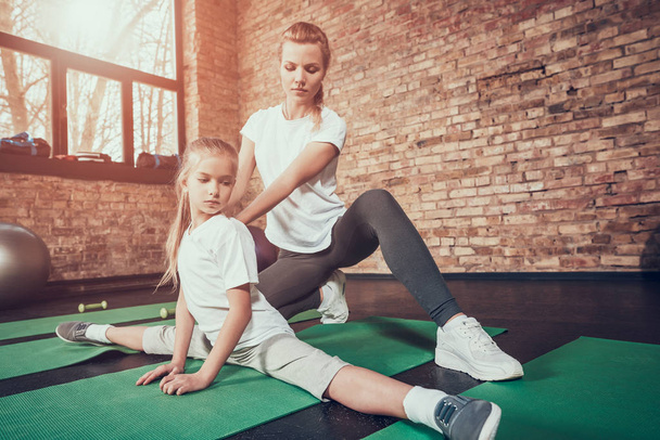 Mother helping her daughter stretching at gym - Foto, Imagen