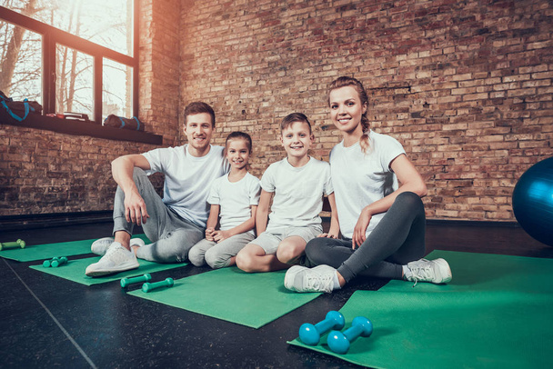 Happy family sitting on green mats after training at gym - Foto, Imagen